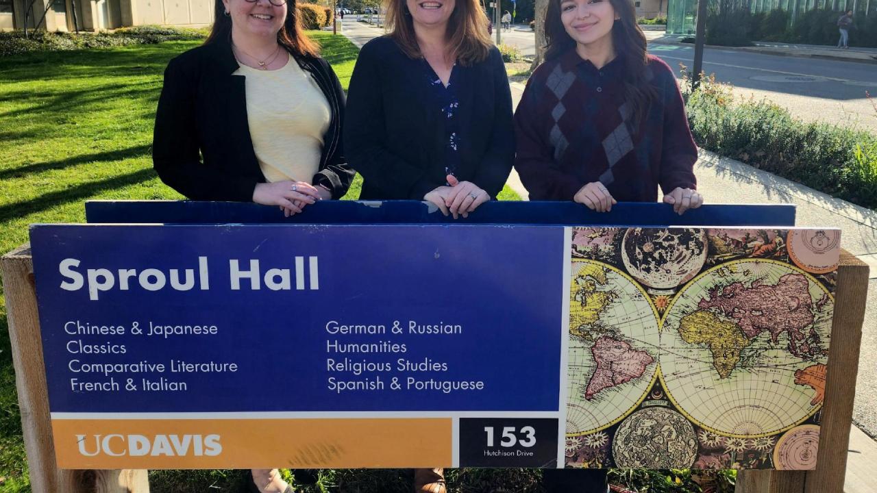 Three women standing behind a sign
