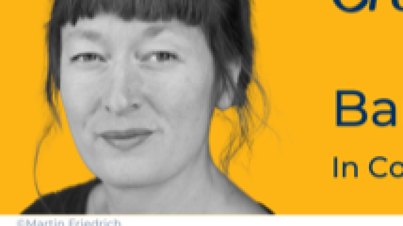 A black and white headshot photo of a woman against a yellow background