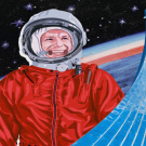 An astronaut in a helmet and red suit looks off into the distance and smiles.