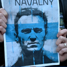 A blue poster for a documentary is held between two hands.