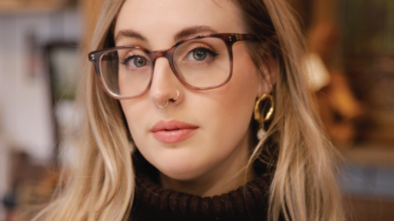 A woman with glasses wearing a black top.