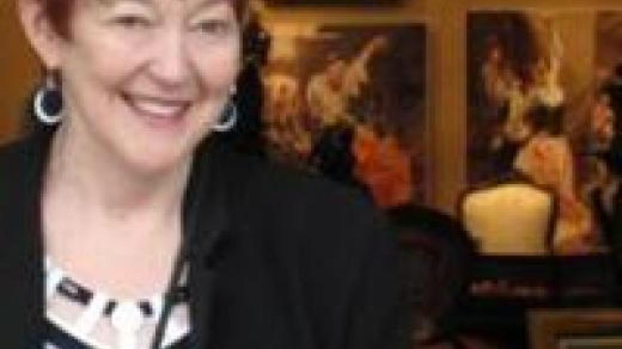 a woman standing and smiling in front of a wall of photos