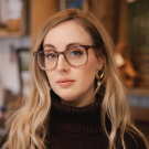 A woman with glasses wearing a black top.