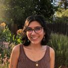 A woman wearing glasses, in nature, smiling