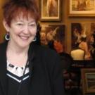 a woman standing and smiling in front of a wall of photos